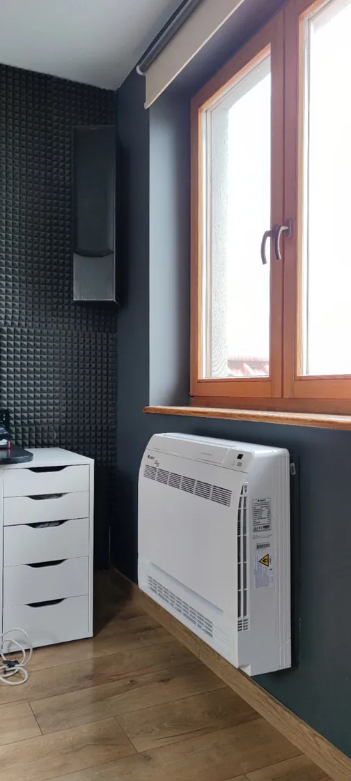 Klimatyzator przypodłogowy Gree przy oknie w pomieszczeniu